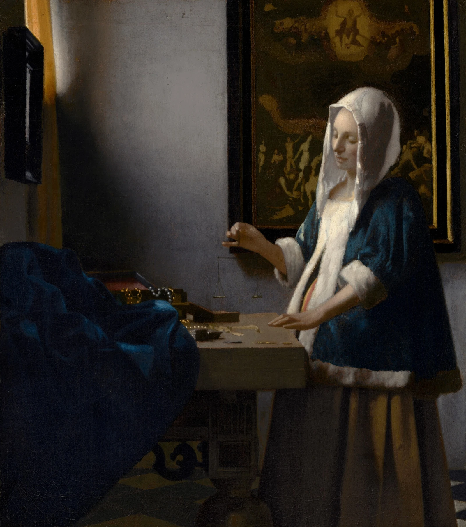 Uma mulher com casaco azul e cobertura branca na cabeça segura uma pequena balança sobre uma mesa com joias. Atrás dela há uma pintura do Juízo Final. A luz entra pela esquerda.